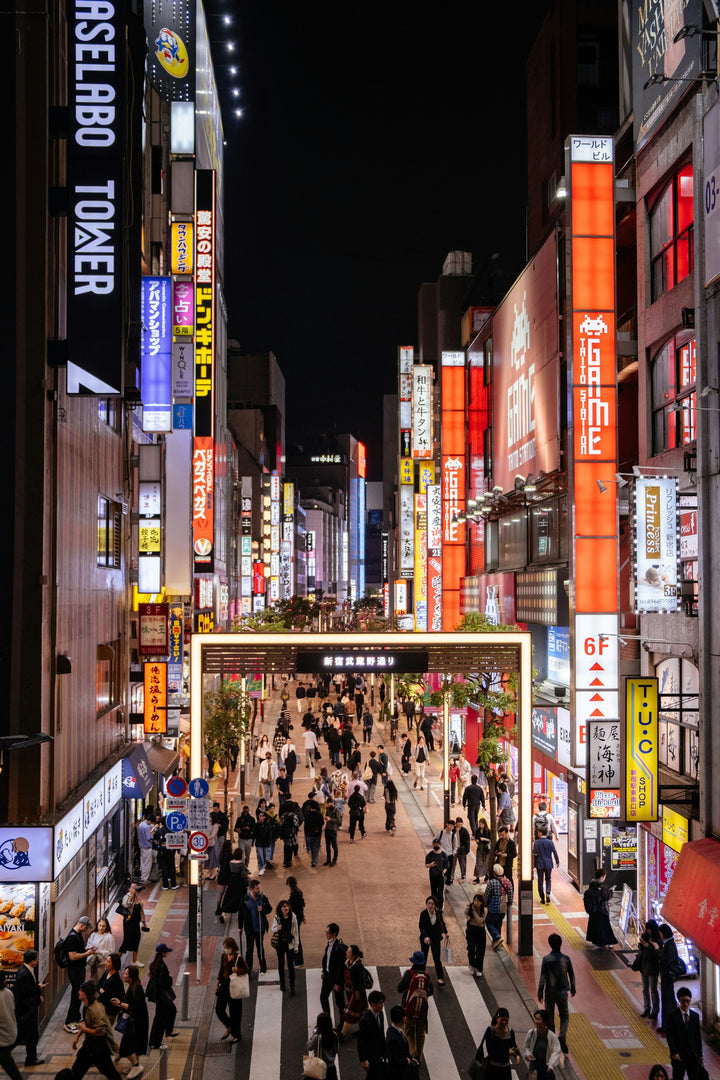 Belebte Straße mit Leuchtreklamen in Tokio bei Nacht